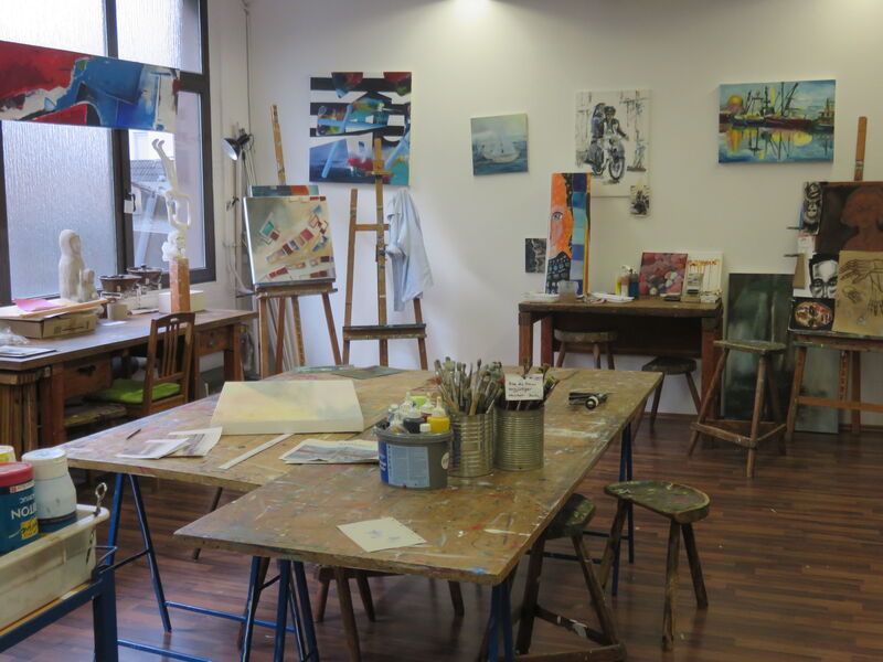 Ein Blick ins Atelier mit seinen Arbeitstischen, Staffeleien und fertigen Bildern an den Wänden.